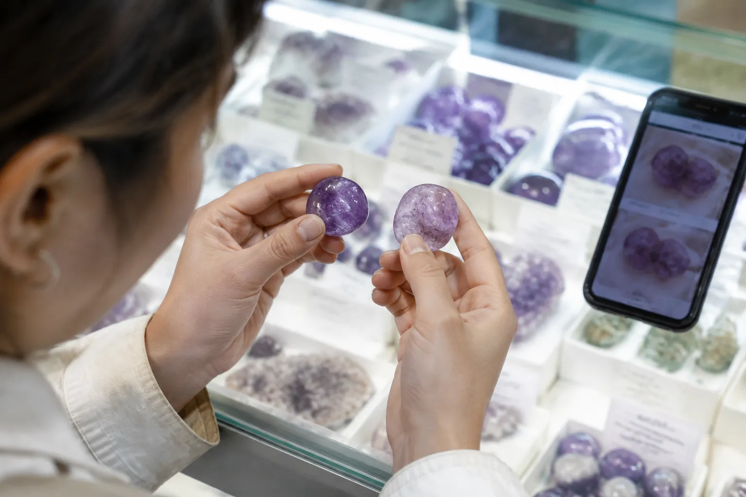 A shopper comparing two similar purple stones with seller photographs and simple specimen labels