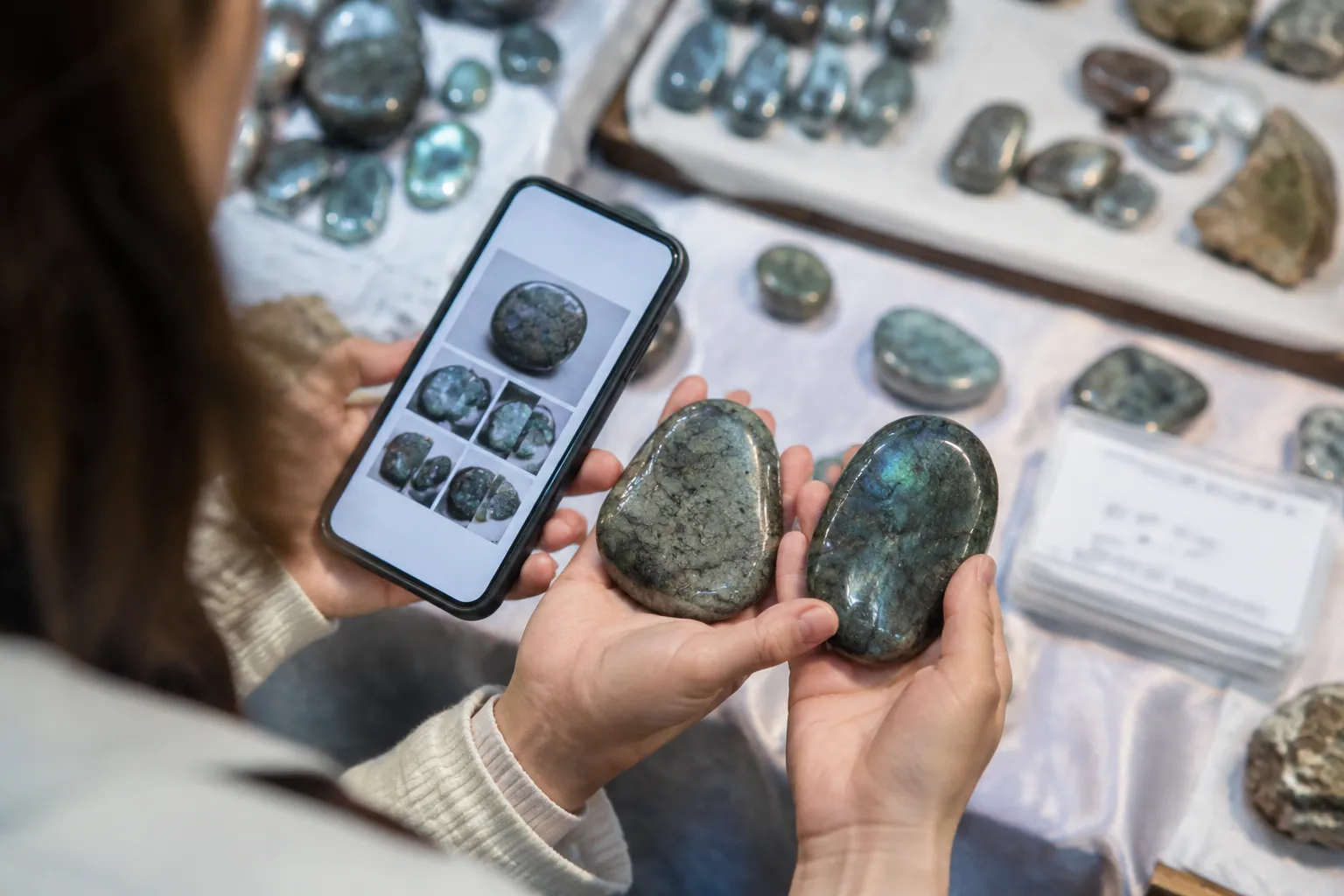 A shopper comparing two polished stones with seller photographs and a partially visible label